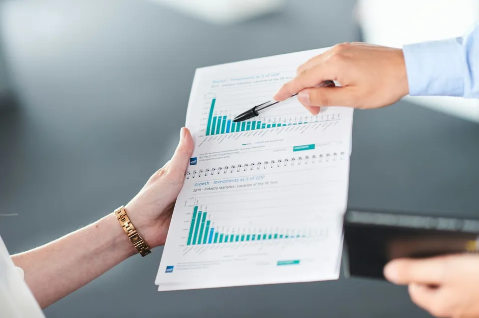 Two people going through a printed report with bar charts